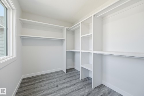 Walk-in closet featuring built-in white shelving and hanging rods, wood-finish flooring, and a single window - 3 Pierwyck Loop, Spruce Grove, AB - Indoor With Storage