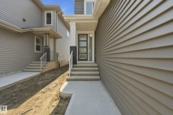 Modern facade featuring a dark entry door with frosted glass inserts, a covered front porch with white pillars, and a multi-level concrete walkway - 