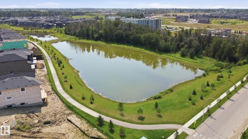 Expansive stormwater pond bordered by a paved walking path, mature trees, and landscaped green space - 3 Pierwyck Loop, Spruce Grove, AB - Outdoor With Body Of Water With View