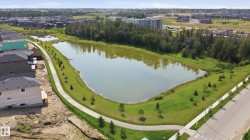 Expansive stormwater pond bordered by a paved walking path, mature trees, and landscaped green space - 