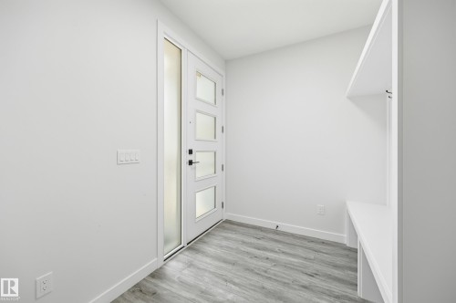 Entryway featuring a modern door with obscured glass panels, a built-in bench, overhead shelving, integrated coat hooks, and wood-finish flooring - 3 Pierwyck Loop, Spruce Grove, AB - Indoor Photo Showing Other Room