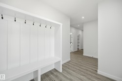 Built-in mudroom bench with storage and board and batten detailing, featuring black coat hooks - 