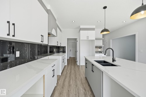 Modern kitchen featuring white cabinetry with matte black hardware, white countertops, and a black marble-effect backsplash - 3 Pierwyck Loop, Spruce Grove, AB - Indoor Photo Showing Kitchen With Double Sink With Upgraded Kitchen