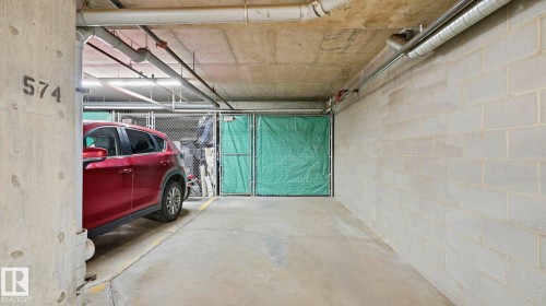 Dedicated parking space featuring concrete flooring, overhead fluorescent lighting, exposed concrete ceiling, and concrete block walls - #361 7805 71 St Nw, Edmonton, AB - Indoor Photo Showing Garage