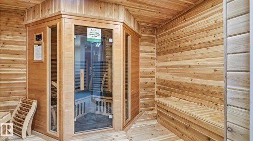 Dedicated sauna room featuring a glass-front enclosure, full wood-paneling, built-in wooden benches, and wood-finish flooring - #361 7805 71 St Nw, Edmonton, AB - Indoor Photo Showing Other Room