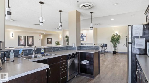 Spacious kitchen area featuring dark wood-finish cabinetry, a double basin stainless steel sink, and a stainless steel dishwasher - #361 7805 71 St Nw, Edmonton, AB - Indoor Photo Showing Kitchen With Double Sink With Upgraded Kitchen