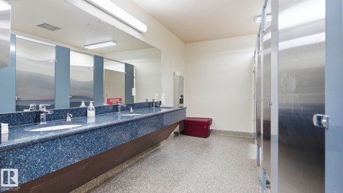 Commercial restroom featuring a long vanity with dual integrated sinks and a speckled blue countertop - #361 7805 71 St Nw, Edmonton, AB - Indoor