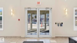 Double glass doors with polished handles, neutral wall paint, and sconce lighting - 