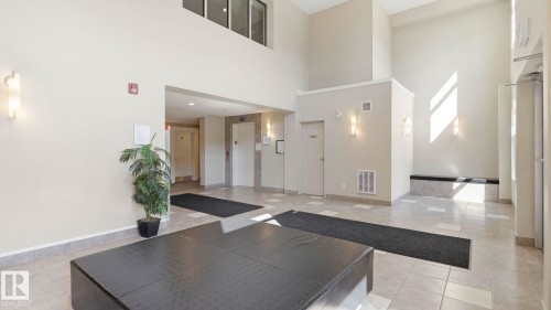 Spacious entry foyer featuring high ceilings, light-toned wall finishes, recessed lighting, and large format tile flooring - #361 7805 71 St Nw, Edmonton, AB - Indoor Photo Showing Other Room