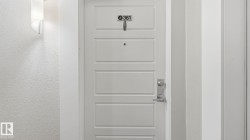 White paneled door with brushed nickel hardware, featuring a modern wall sconce and textured wall finish - 