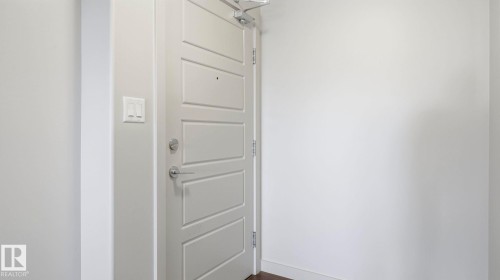 Modern entry door with five horizontal panels, satin nickel hardware, and a door closer mechanism - #361 7805 71 St Nw, Edmonton, AB - Indoor Photo Showing Other Room