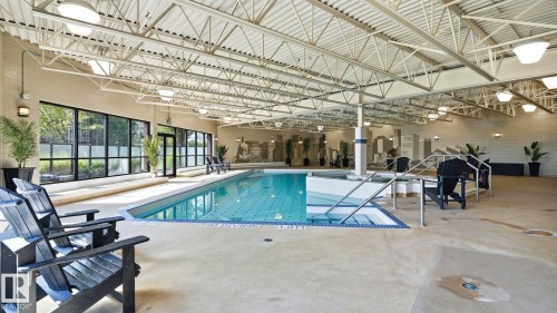 Indoor swimming pool with concrete decking, large windows, exposed ceiling trusses, and recessed lighting - #361 7805 71 St Nw, Edmonton, AB - Indoor Photo Showing Other Room With In Ground Pool