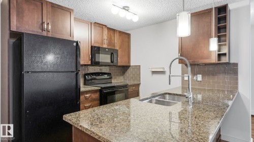 Kitchen featuring granite countertops, wood-finish cabinetry, a stainless steel double basin sink with a gooseneck faucet, and a subway tile backsplash - #361 7805 71 St Nw, Edmonton, AB - Indoor Photo Showing Kitchen With Double Sink