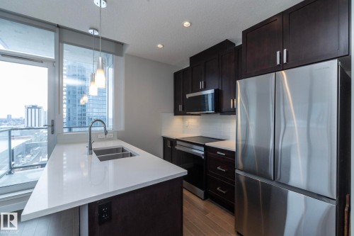 Modern kitchen featuring dark wood-finish cabinetry and stainless steel appliances - #1201 10238 103 St Nw, Edmonton, AB - Indoor Photo Showing Kitchen With Stainless Steel Kitchen With Double Sink With Upgraded Kitchen