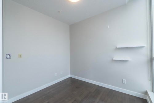 Neutral wall finishes with crisp white trim, wood-finish flooring, and built-in floating shelves - #1201 10238 103 St Nw, Edmonton, AB - Indoor Photo Showing Other Room
