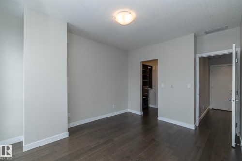 Spacious room featuring dark wood-finish flooring, light gray walls, white baseboards, and a flush mount ceiling light - #1201 10238 103 St Nw, Edmonton, AB - Indoor Photo Showing Other Room