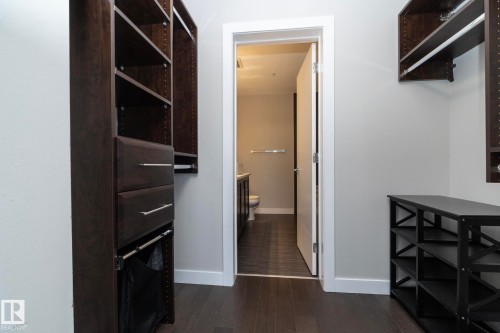 Custom closet system featuring dark wood-finish cabinetry, integrated shelving, and drawers with brushed nickel hardware - #1201 10238 103 St Nw, Edmonton, AB - Indoor Photo Showing Other Room