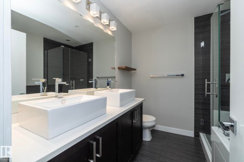 Bathroom featuring a double vanity with rectangular vessel sinks, white countertops, and dark wood-finish cabinetry - #1201 10238 103 St Nw, Edmonton, AB - Indoor Photo Showing Bathroom