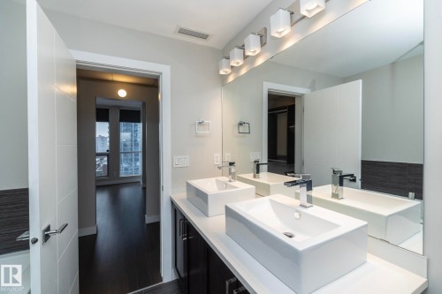 Dual rectangular vessel sinks with chrome faucets, a large vanity mirror, and a linear vanity light fixture - #1201 10238 103 St Nw, Edmonton, AB - Indoor Photo Showing Bathroom