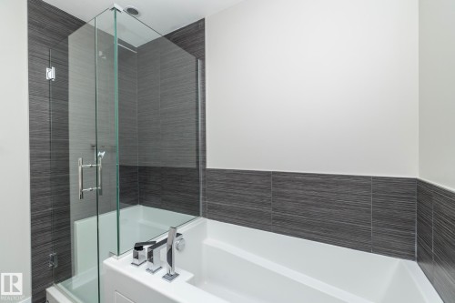 Contemporary tub/shower combination featuring a frameless glass enclosure and a full tile surround - #1201 10238 103 St Nw, Edmonton, AB - Indoor Photo Showing Bathroom