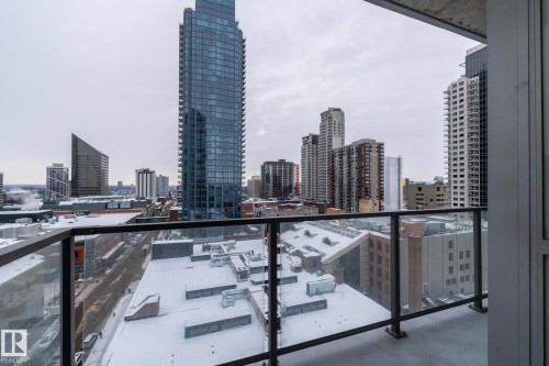 Balcony with glass panel railing and concrete flooring overlooking a cityscape with multiple high-rise buildings - #1201 10238 103 St Nw, Edmonton, AB - Outdoor With Balcony