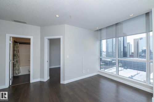 Floor-to-ceiling windows with roller shades, recessed ceiling lighting, and dark wood-finish flooring - #1201 10238 103 St Nw, Edmonton, AB - Indoor Photo Showing Other Room