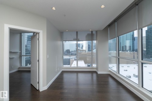 Expansive room featuring floor-to-ceiling windows with roller shades, recessed lighting, wood-finish flooring, and crisp white trim - #1201 10238 103 St Nw, Edmonton, AB - Indoor Photo Showing Other Room