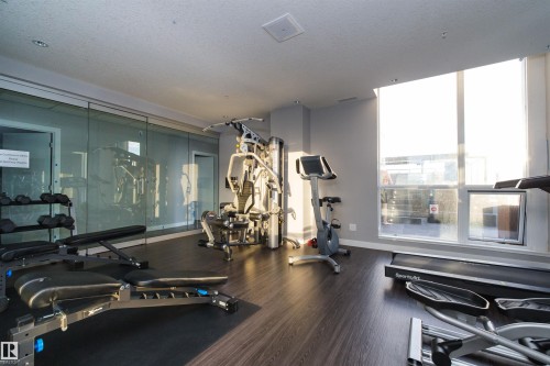 Dedicated fitness space featuring wood-finish flooring and large windows with roller shades - #1201 10238 103 St Nw, Edmonton, AB - Indoor Photo Showing Gym Room