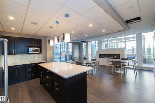 Open-concept space featuring wood-finish flooring and a contemporary kitchen with dark cabinetry, light countertops, and a full appliance suite - #1201 10238 103 St Nw, Edmonton, AB - Indoor