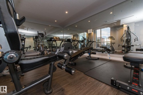 Fitness center featuring wood-finish flooring, full-height mirrored walls, recessed lighting, and large windows - #1201 10238 103 St Nw, Edmonton, AB - Indoor Photo Showing Gym Room