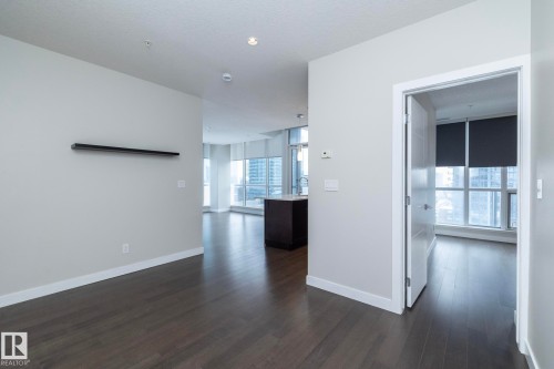 Open-concept living area featuring dark wood-finish flooring, light grey wall paint, white baseboards, and recessed lighting - #1201 10238 103 St Nw, Edmonton, AB - Indoor Photo Showing Other Room