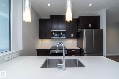 Kitchen island with an undermount stainless steel sink and a contemporary chrome faucet - #1201 10238 103 St Nw, Edmonton, AB - Indoor Photo Showing Kitchen With Double Sink