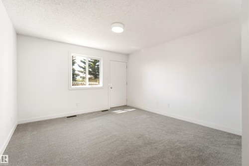Spacious room featuring new gray carpeting, crisp white walls, a bright window with a white frame, and a flush-mount ceiling light - #4 7604 29 Av Nw, Edmonton, AB - Indoor Photo Showing Other Room