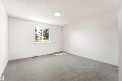 Spacious room featuring new gray carpeting, crisp white walls, a bright window with a white frame, and a flush-mount ceiling light - 