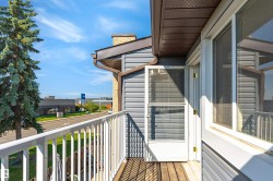 Exterior balcony featuring wood-finish flooring, white railing, and grey horizontal siding - 