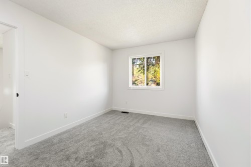 Neutral-toned room featuring a window with white trim, light grey patterned carpeting, crisp white walls, and matching white baseboards - #4 7604 29 Av Nw, Edmonton, AB - Indoor Photo Showing Other Room