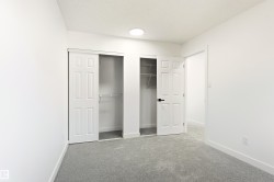 Room featuring light gray carpeting, white walls, and a built-in closet with sliding panel doors and wire shelving - 