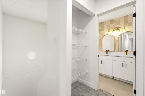 Contemporary bathroom vanity with dual arched gold-framed mirrors, a gold-finish light fixture, and white cabinetry with matte black hardware - #4 7604 29 Av Nw, Edmonton, AB - Indoor With Storage