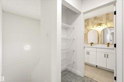 Contemporary bathroom vanity with dual arched gold-framed mirrors, a gold-finish light fixture, and white cabinetry with matte black hardware - 