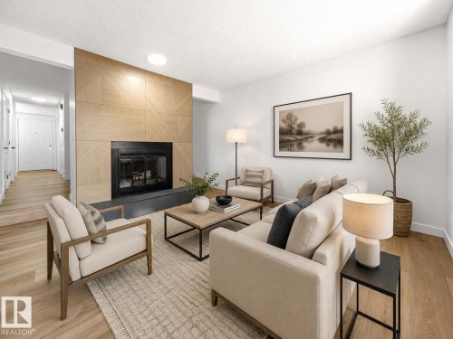 Living area with a contemporary fireplace featuring a wood-panel accent wall and dark stone hearth - #4 7604 29 Av Nw, Edmonton, AB - Indoor Photo Showing Living Room With Fireplace