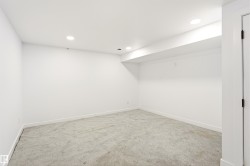 Neutral-toned carpeted room featuring white walls and recessed ceiling lighting - 