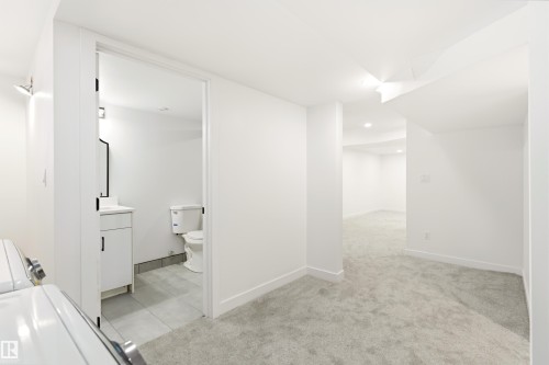 Spacious lower level featuring plush gray carpeting throughout, recessed lighting, and crisp white walls - #4 7604 29 Av Nw, Edmonton, AB - Indoor Photo Showing Other Room
