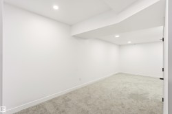 Spacious interior room featuring light gray carpeting, white walls, and recessed lighting - 