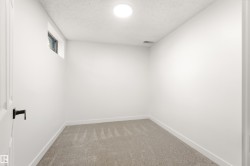 Neutral-toned carpeting grounds this room with a white door and dark hardware - 