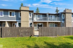 Townhome exterior featuring blue horizontal siding, stucco accents, and a private fenced yard with a wooden gate - 