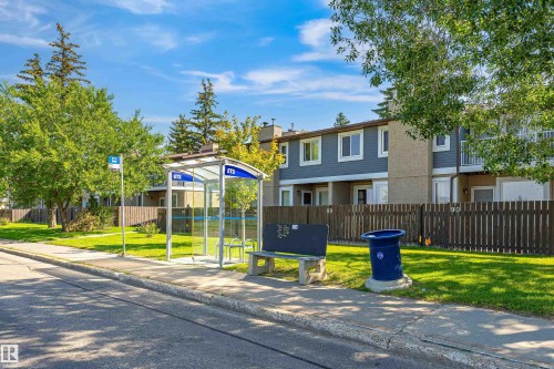 Street scene featuring a bus stop with a shelter and bench - #4 7604 29 Av Nw, Edmonton, AB - Outdoor