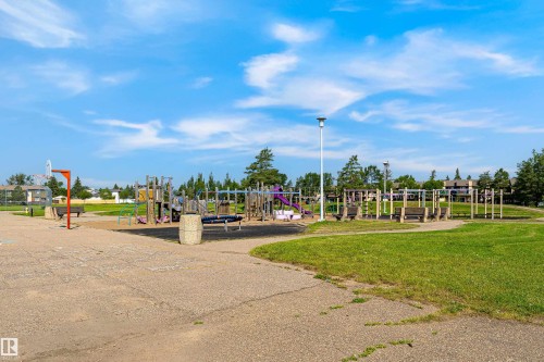 Community park with green spaces, playground equipment, basketball hoop, and a paved pathway - #4 7604 29 Av Nw, Edmonton, AB - Outdoor With View