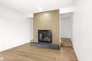 Fireplace featuring a light wood-finish surround with a geometric pattern, black firebox, and dark tile hearth - #4 7604 29 Av Nw, Edmonton, AB  - Indoor With Fireplace 