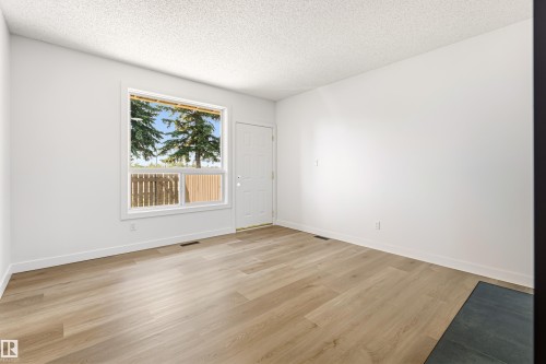 Spacious room featuring wood-finish flooring, crisp white walls, and a textured ceiling - #4 7604 29 Av Nw, Edmonton, AB - Indoor Photo Showing Other Room