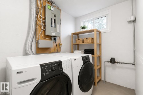 Dedicated laundry area featuring a front-loading washer and dryer, a functional window, and light wood shelving - 12235 104 Street Nw, Edmonton, AB - Indoor Photo Showing Laundry Room